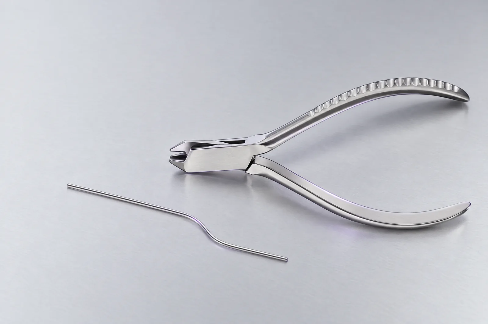 Mise en scène éditoriale générée par IA d’une pince à plier près d’un fil orthodontique coudé, sans patient